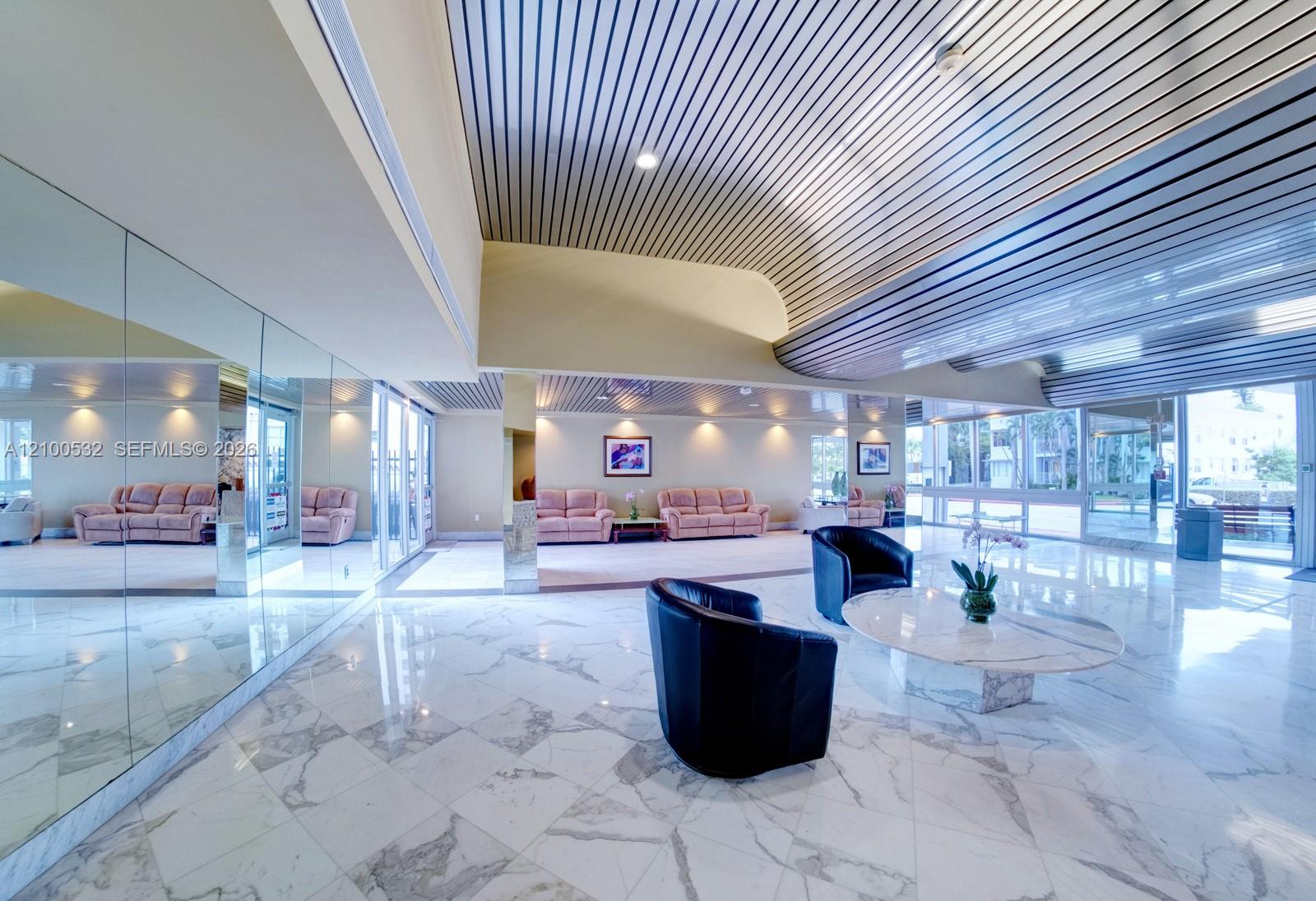 Polished stone flooring, mirrored wall panels, linear metal ceiling detailing, and recessed LED lighting