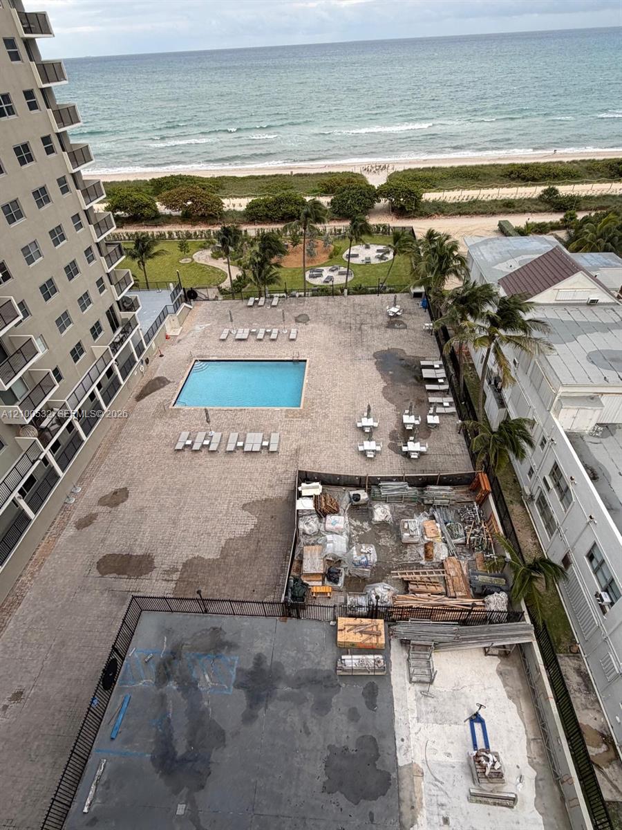 Outdoor pool area featuring a paved deck, palm trees, and direct proximity to the oceanfront