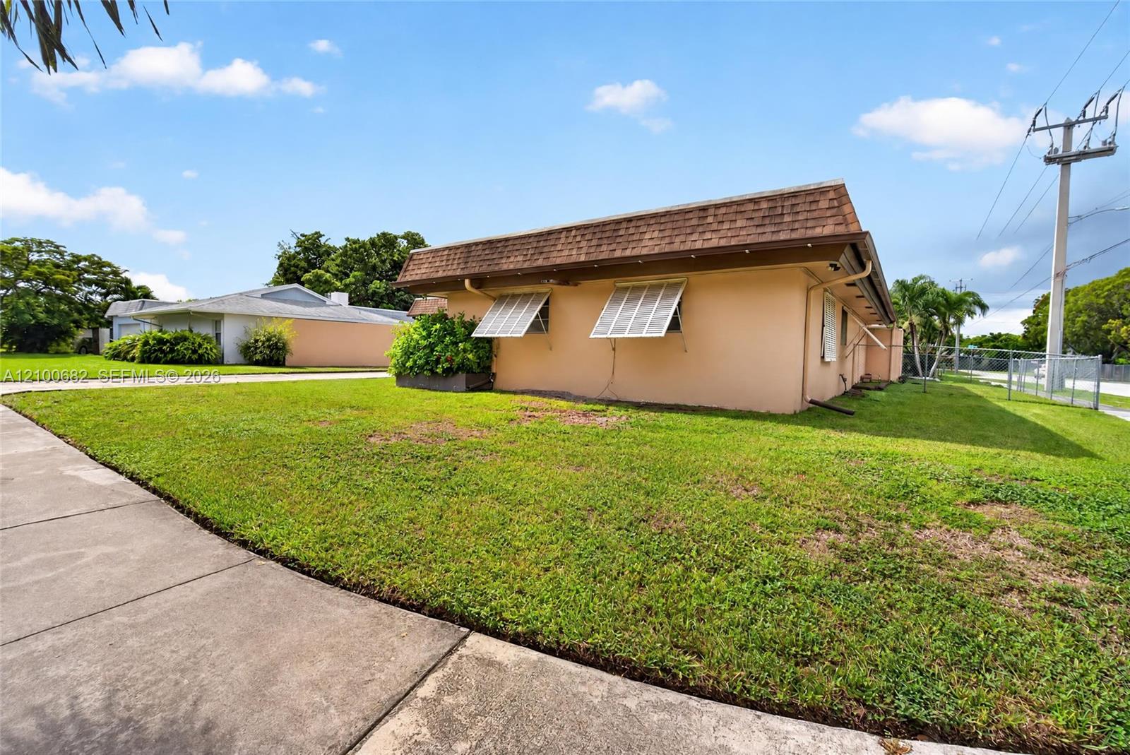Single-story residence with a 2012 shingled mansard roofline, and situated on a level corner lot with concrete sidewalk access