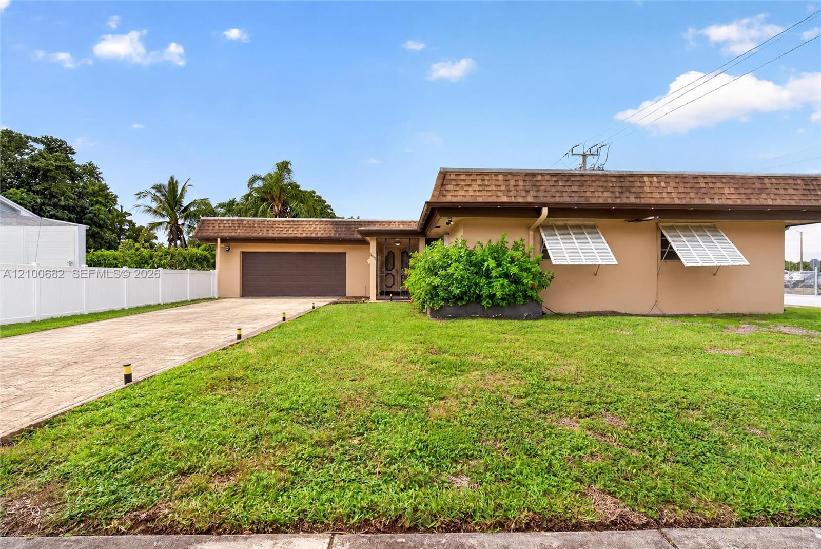 Single-story exterior featuring a concrete driveway, attached 2 car garage, metal bahama window shutters in the front *