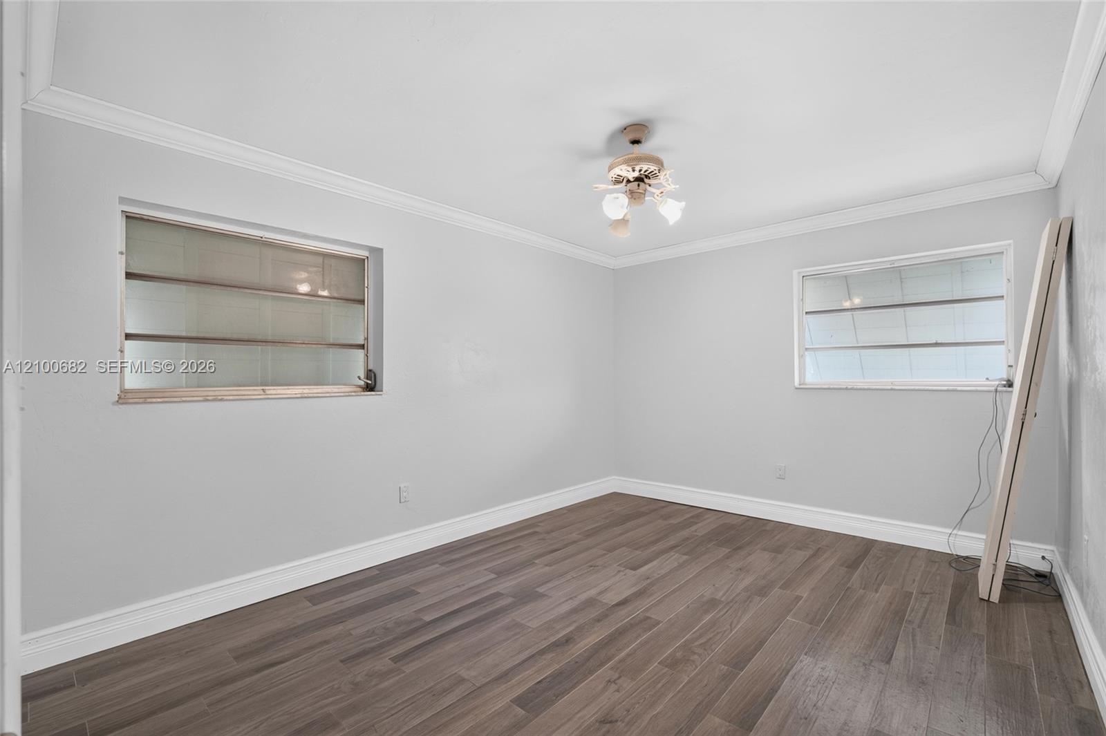 Third bedroom featuring vinyl wood-finish flooring, neutral wall tones, crown molding and newer baseboards*