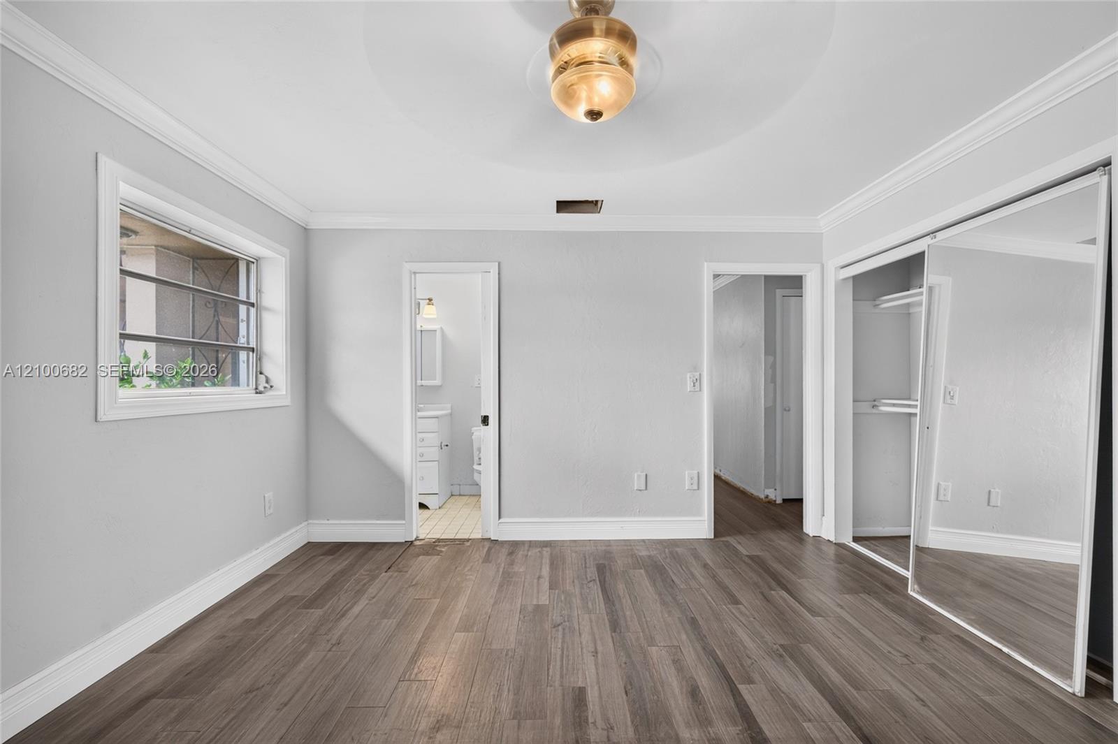 Another view of the main bedroom featuring crown molding, newer baseboards and framed windows *