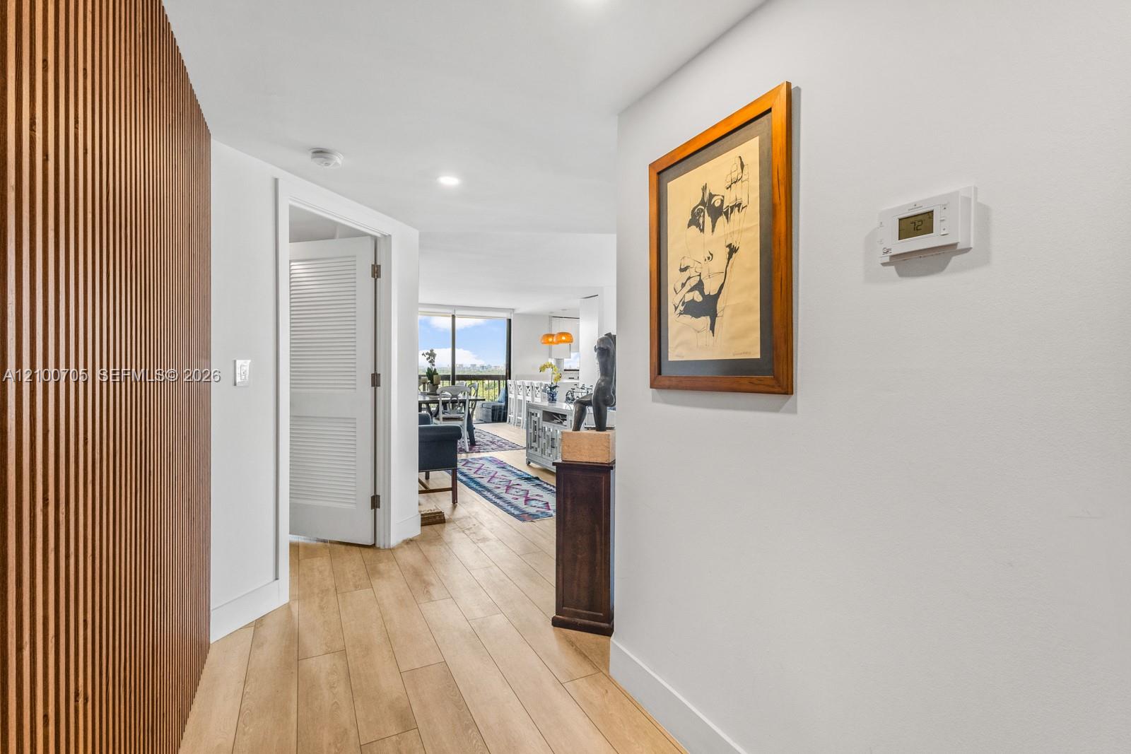 Interior hallway featuring a floor-to-ceiling vertical wood slat accent wall, recessed lighting, and wood-finish flooring