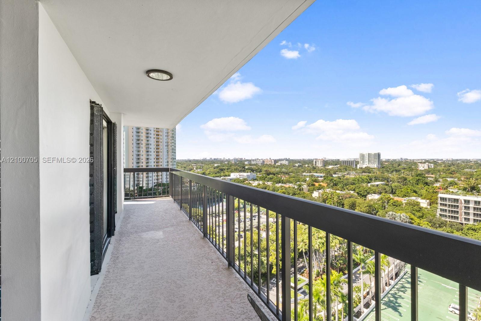 Covered balcony featuring textured flooring, recessed lighting, and a black metal railing