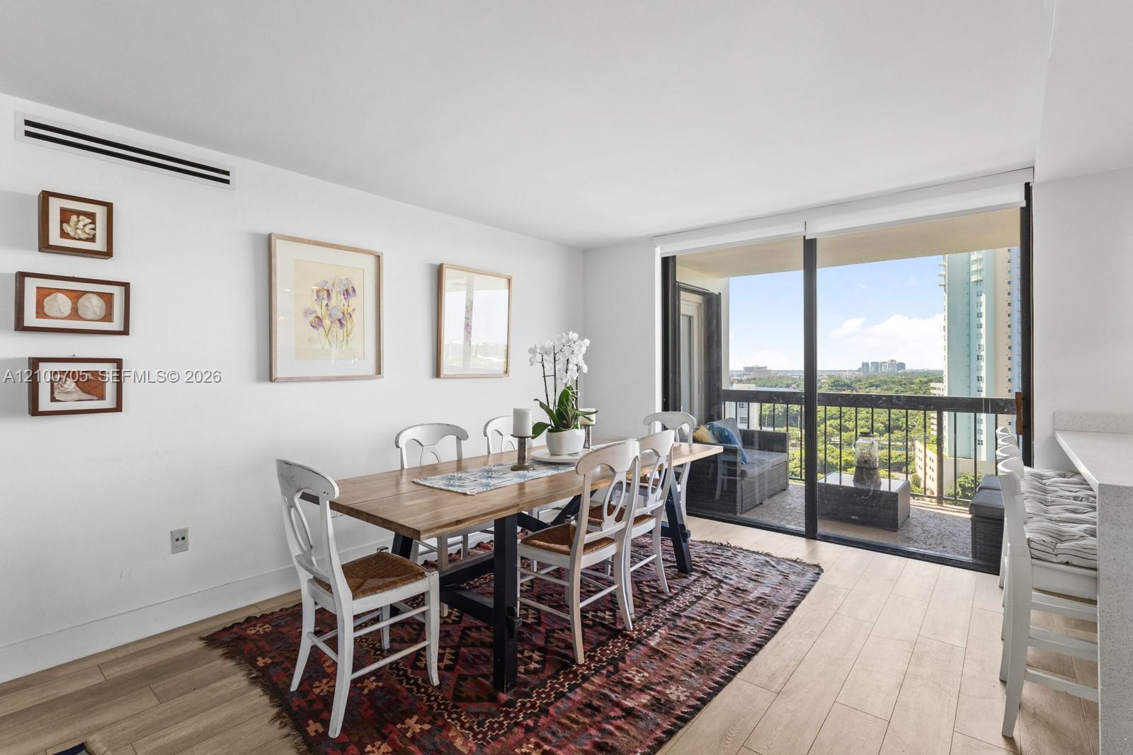 Dining area featuring wood-finish flooring, floor-to-ceiling sliding glass doors, and access to an exterior balcony