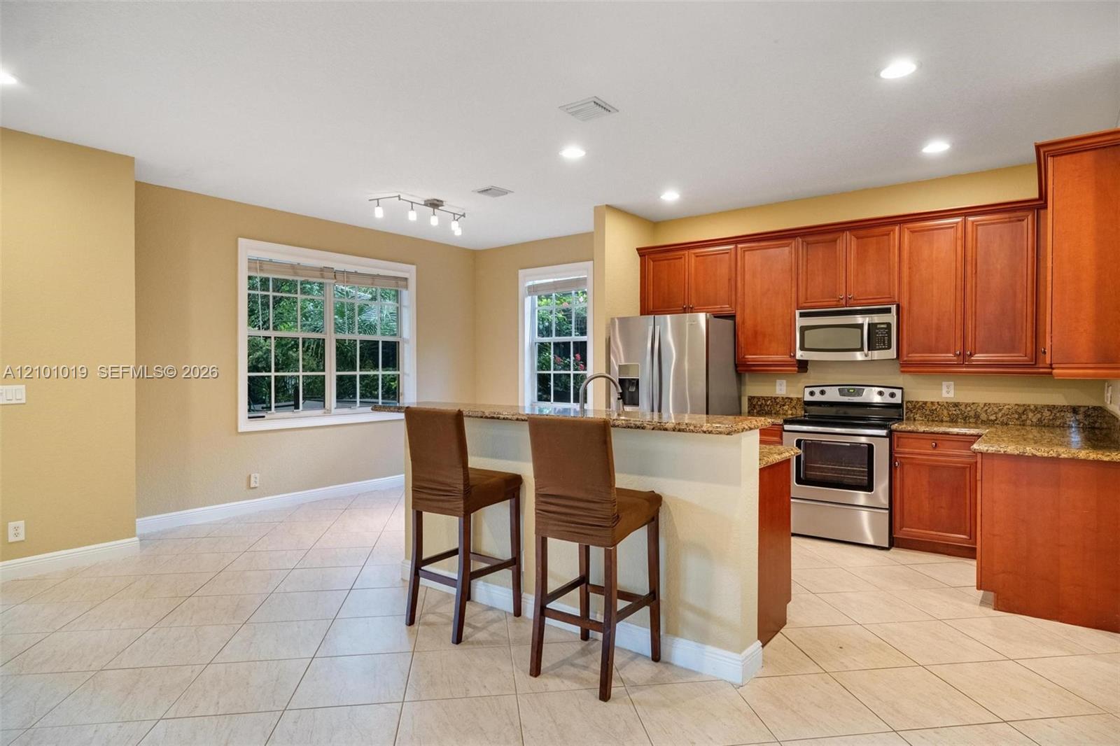 Kitchen featuring wooden cabinetry, stone-surface countertops, tile flooring, recessed lighting, and stainless steel appliances