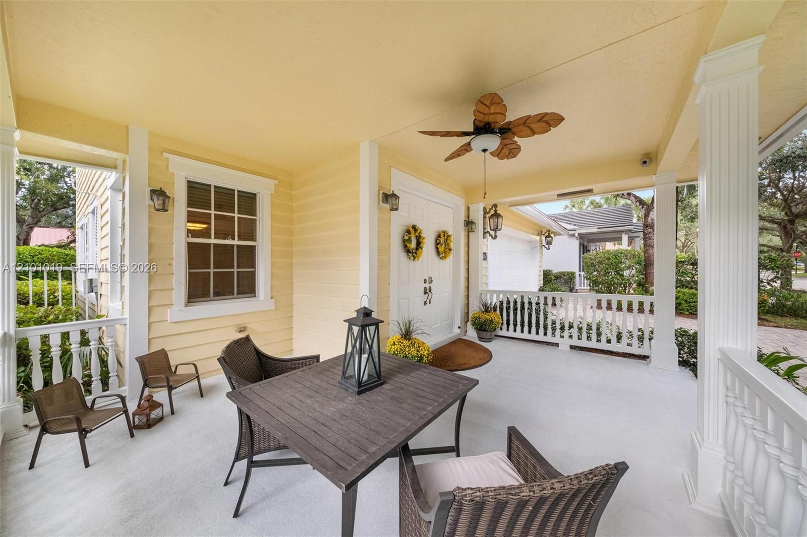 Covered front porch featuring white railings, structural columns, a ceiling-mounted fan, and double-entry doors Covered front porch featuring white railings, structural columns, a ceiling-mounted fan, and double-entry doors