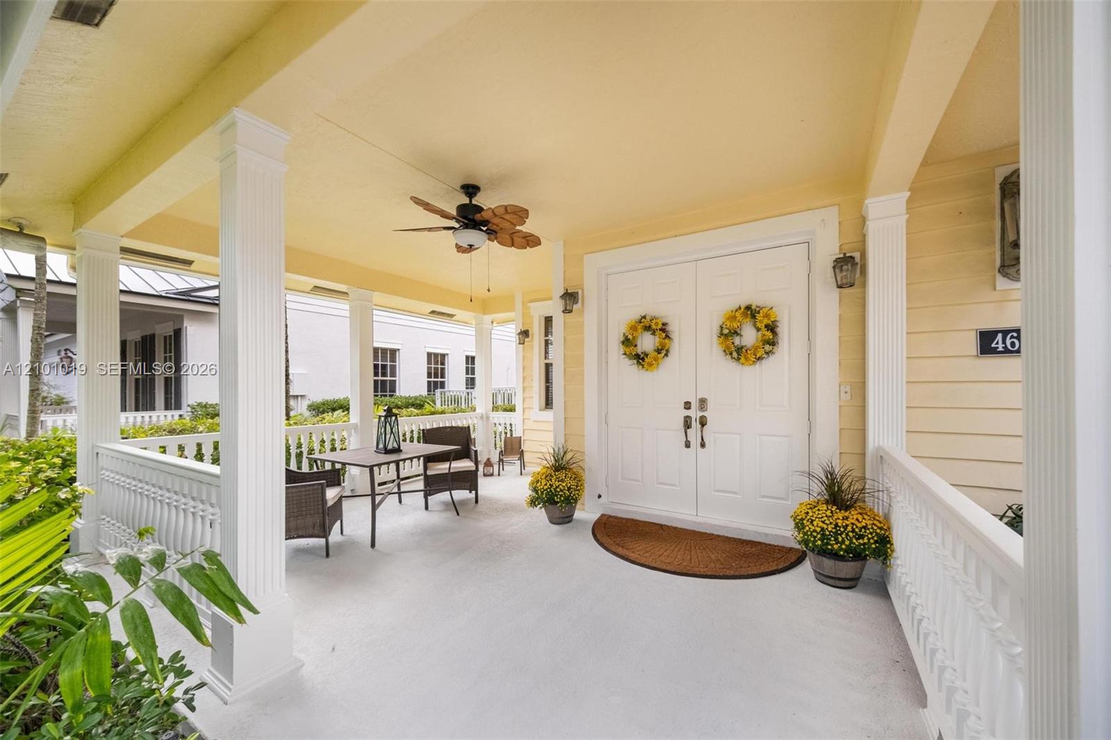 Covered front porch featuring white structural columns, horizontal lap siding, double-door entry, and a ceiling-mounted fan Covered front porch featuring white structural columns, horizontal lap siding, double-door entry, and a ceiling-mounted fan