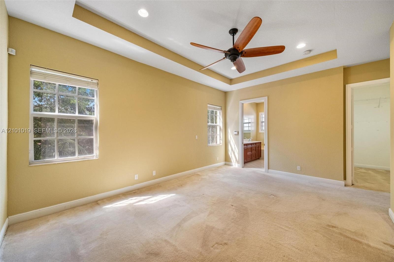 Tray ceiling with recessed lighting, central wood-blade ceiling fan, and dual window openings