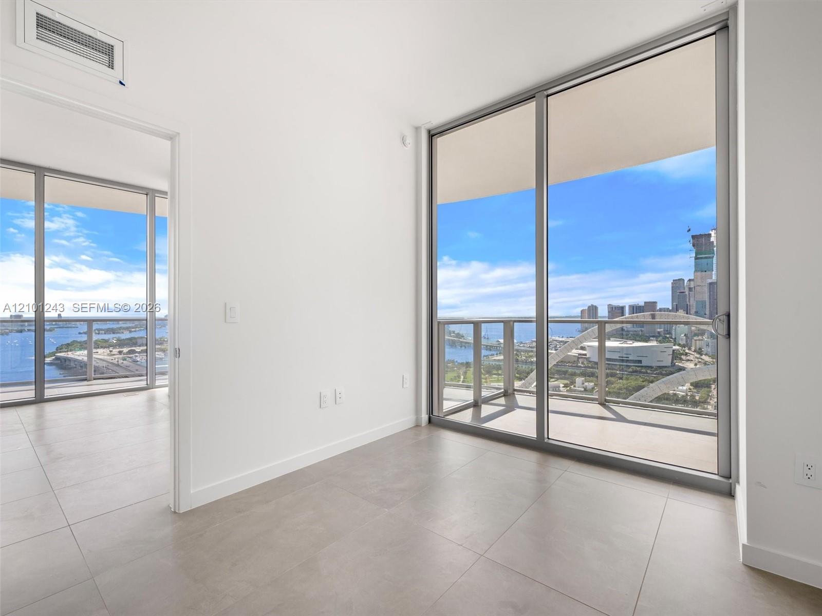 Floor-to-ceiling glass sliding doors, large-format tile flooring, and metal-framed balcony railings
