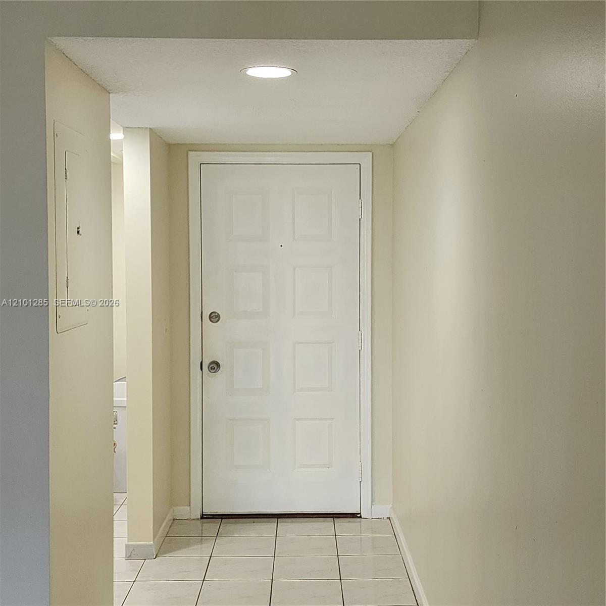Entryway featuring a white eight-panel door, neutral tile flooring, and recessed ceiling lighting