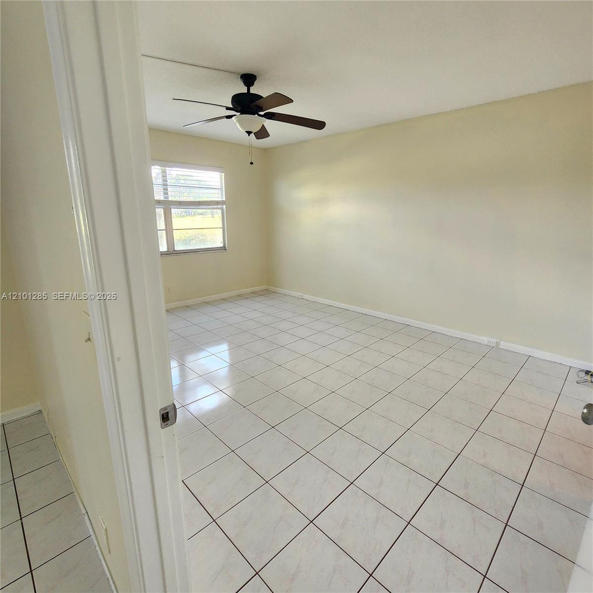 Interior space featuring neutral wall paint, large-format tile flooring, and a multi-blade ceiling fan with an integrated light fixture