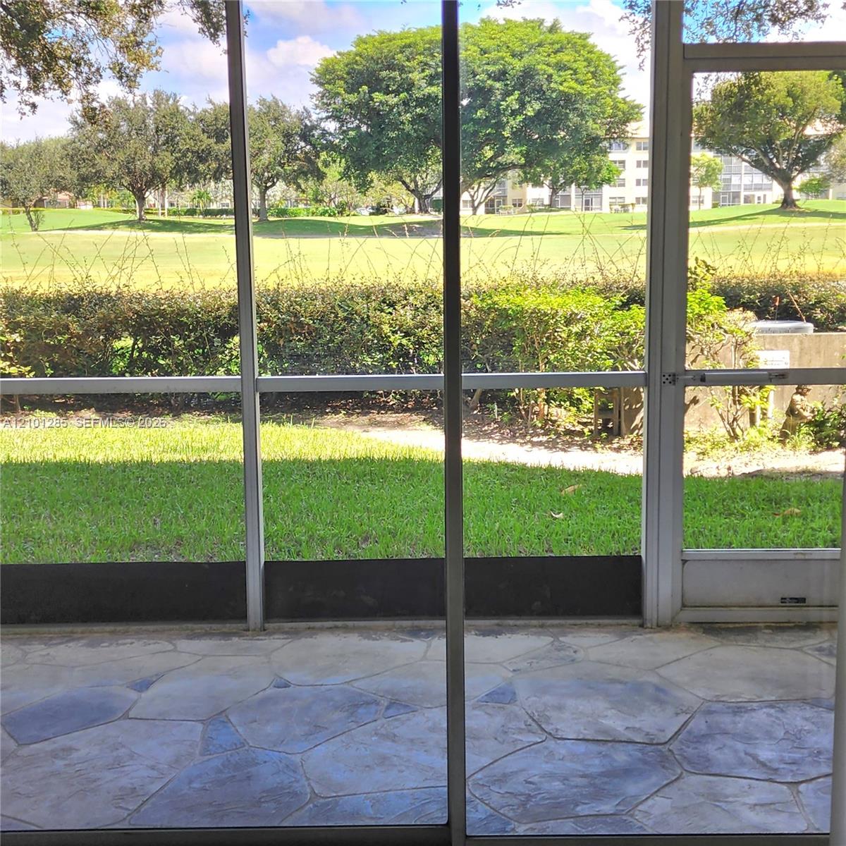 Screened-in patio with flagstone-patterned flooring and direct access to an outdoor area with mature landscaping