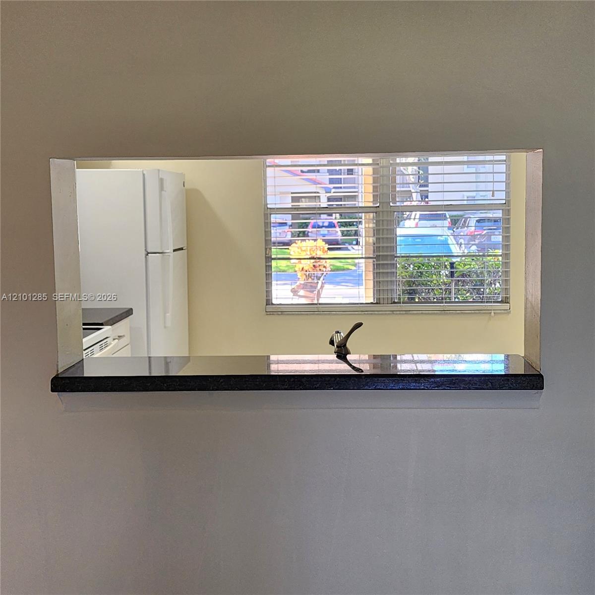 Pass-through window featuring a dark stone countertop and a polished metal faucet