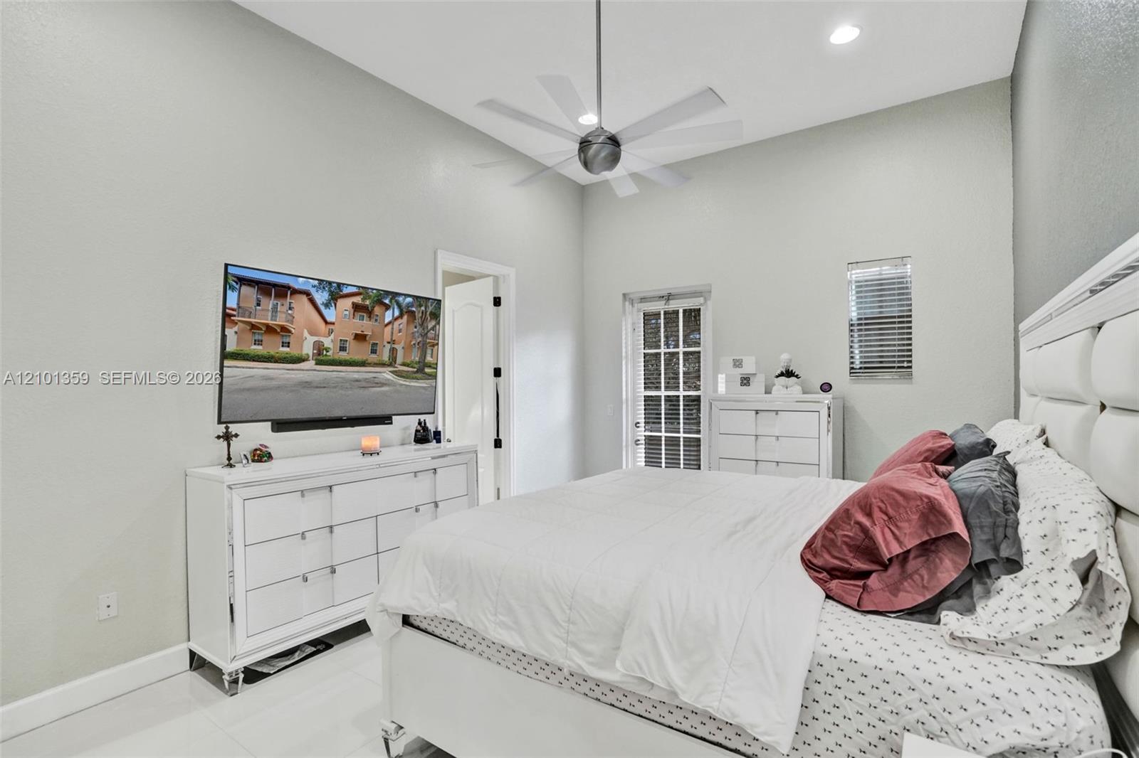 High-ceiling room featuring recessed lighting, a multi-blade ceiling fan, light-toned flooring, and a glass-paneled exterior door