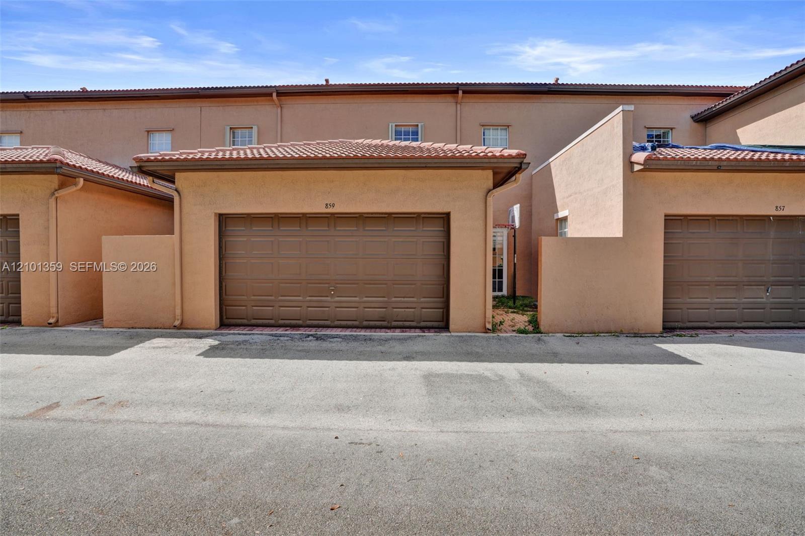 Stucco exterior with mission-style tile roofing and attached single-car garage featuring a paneled door
