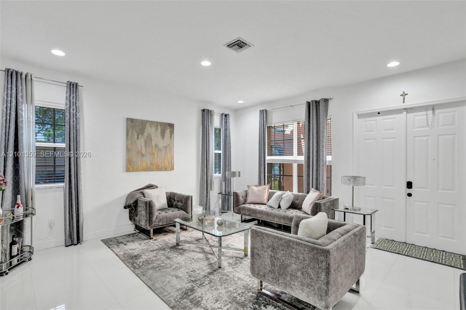 Living area featuring large-format tile flooring, recessed lighting, and double-entry doors