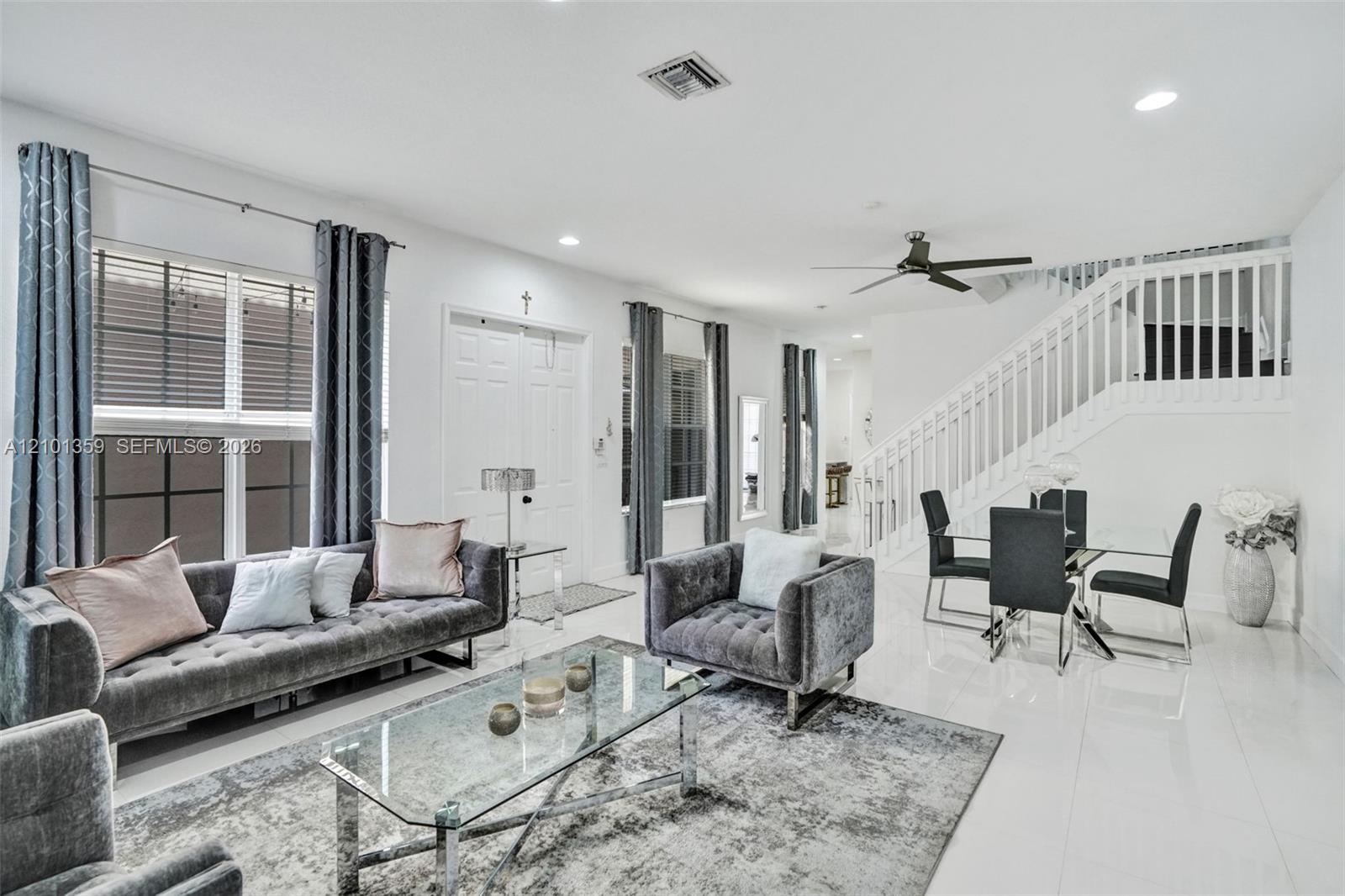 Open-concept living space featuring high-gloss tile flooring, recessed lighting, white stair railing with balusters, and a ceiling fan