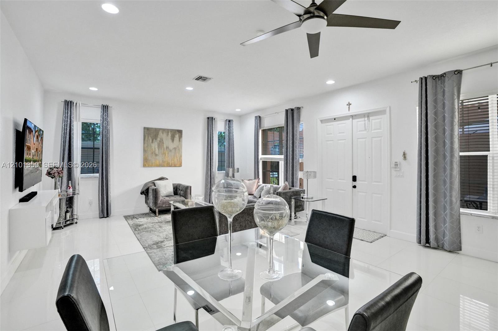 Open-concept living space featuring high ceilings, polished tile flooring, recessed lighting, and a modern ceiling fan