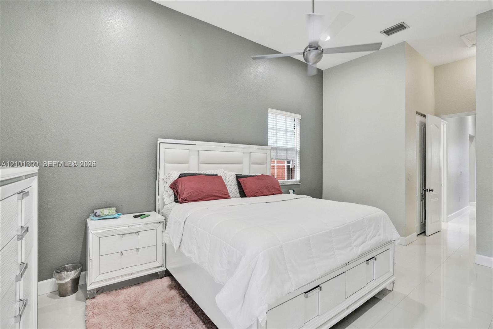 High-ceilinged room with light-toned tile flooring, neutral wall finish, and a ceiling-mounted fan