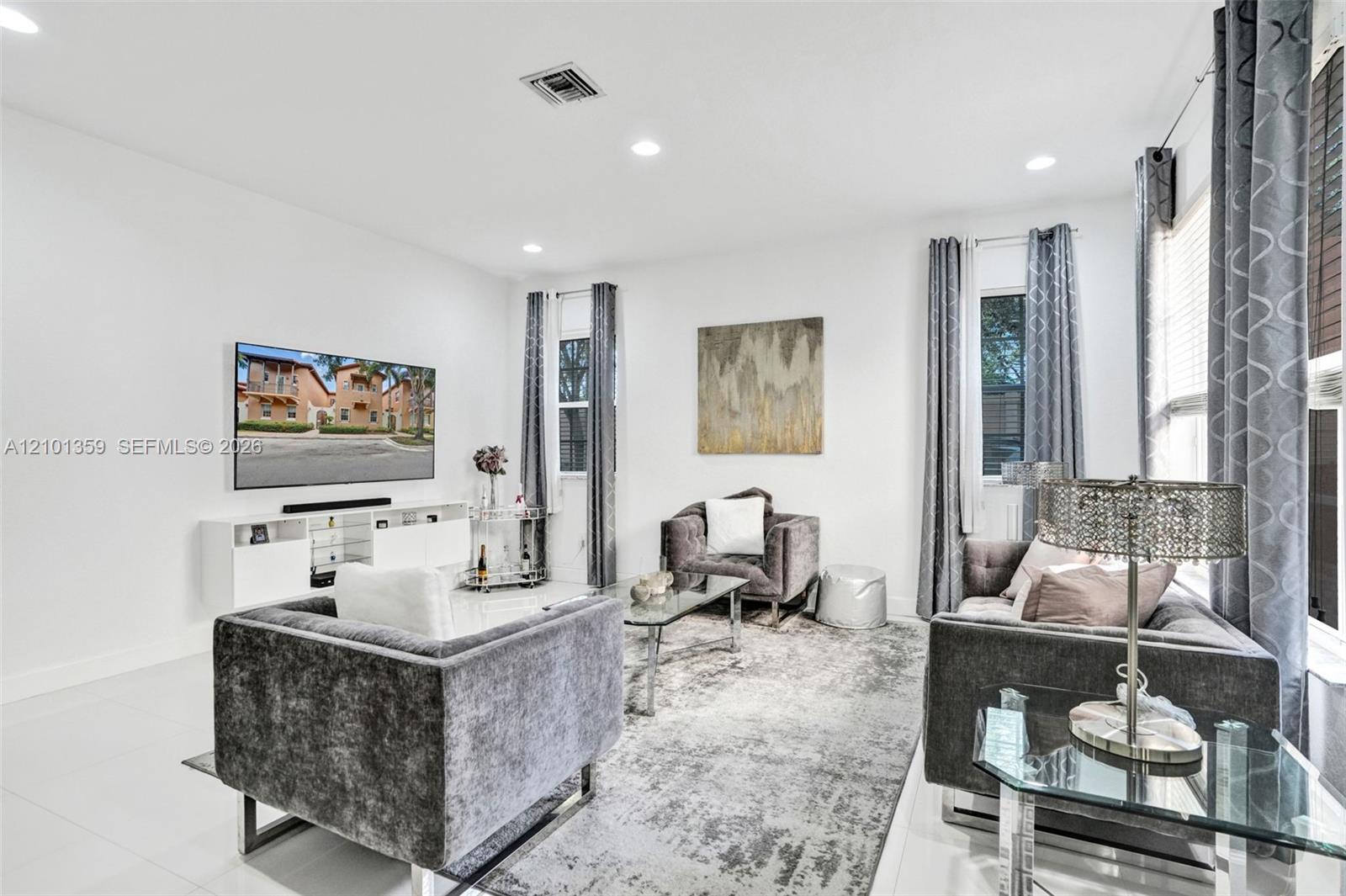 Living area featuring neutral wall tones, large-format tile flooring, and recessed ceiling lighting