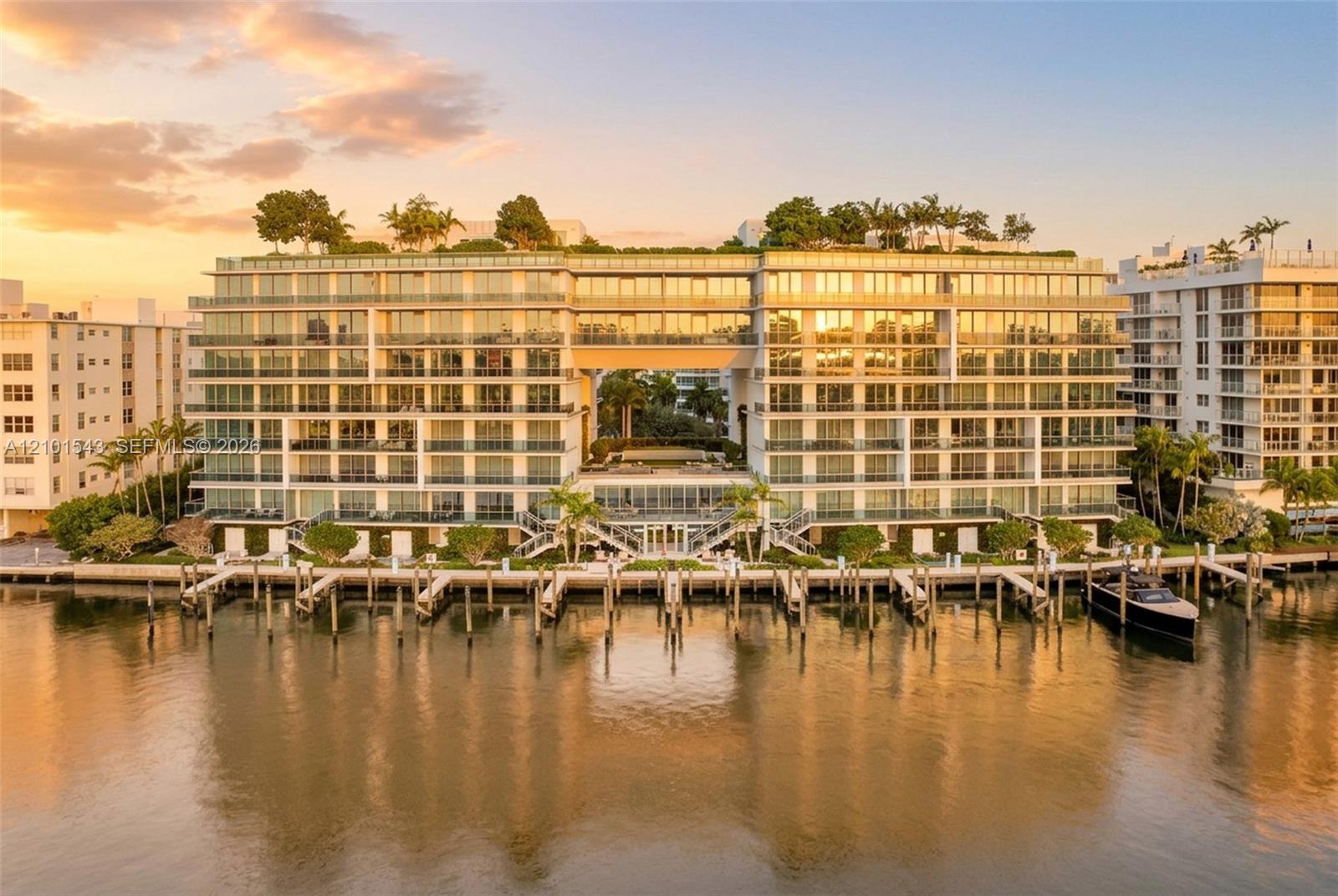 Waterfront residential building featuring floor-to-ceiling glass exteriors, expansive private balconies, a rooftop garden, and multiple deep-water boat slips