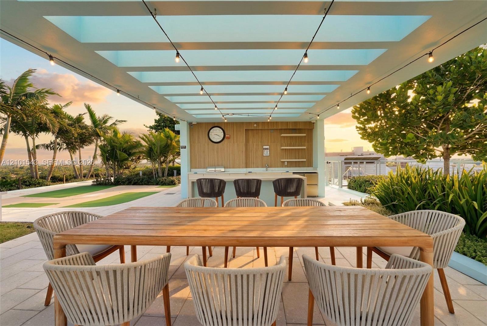 Covered outdoor terrace featuring a wood-paneled wet bar, stone-finished countertop, pergola structure, and light-tone tile flooring