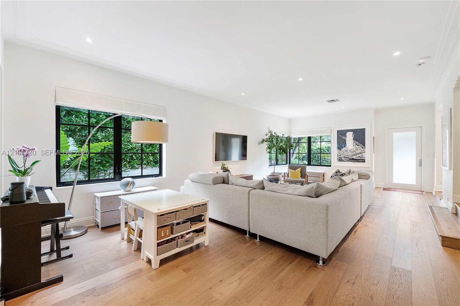 Open-concept room featuring wide-plank wood-finish flooring, recessed lighting, and large windows with black frames