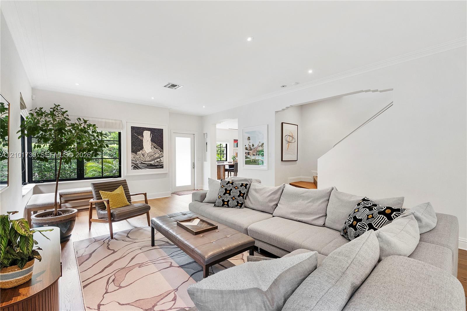 Living area featuring wood-finish flooring, recessed lighting, crown molding, and black-trimmed multi-pane windows