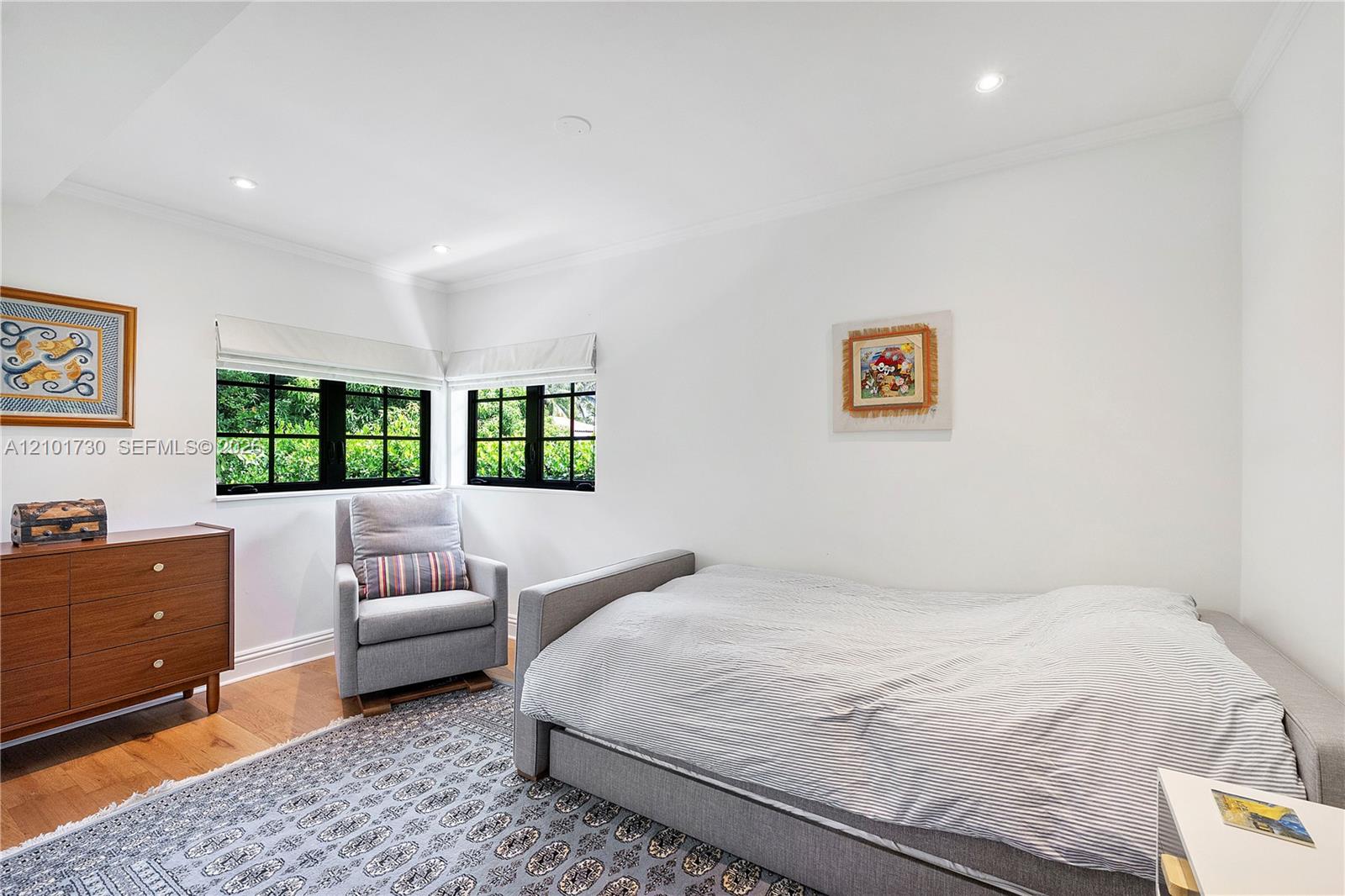 Corner room featuring wood-finish flooring, recessed lighting, and black-framed multi-pane windows