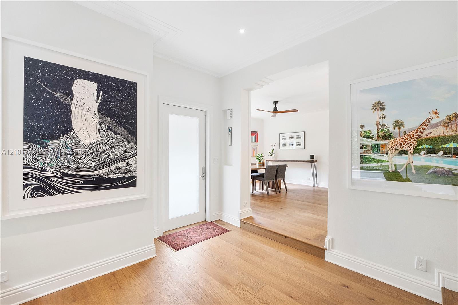 Foyer featuring wood-finish flooring, a recessed entryway with a frosted-glass door, and crown molding