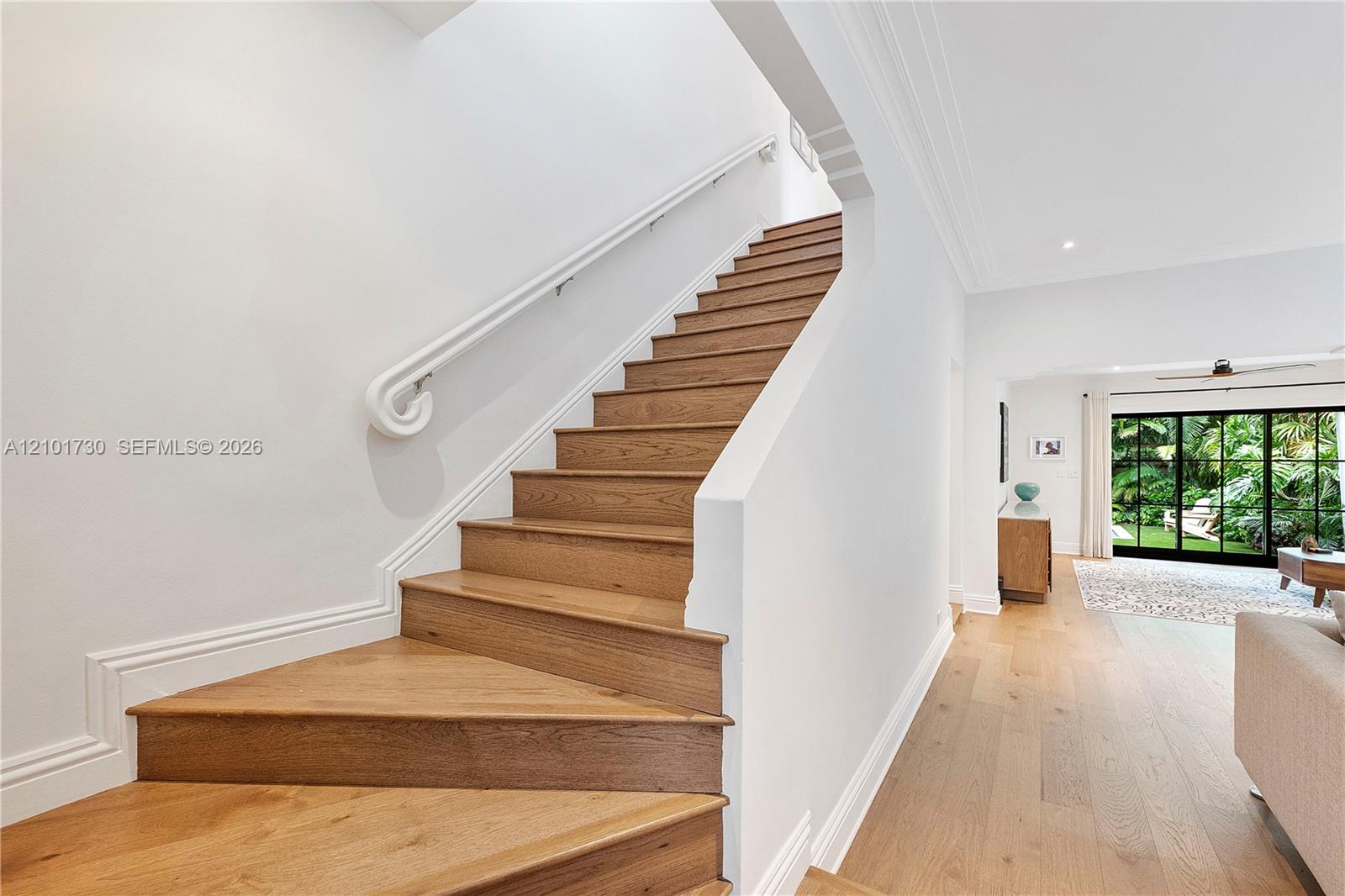 Staircase featuring wood-finish treads, a white handrail, and white millwork