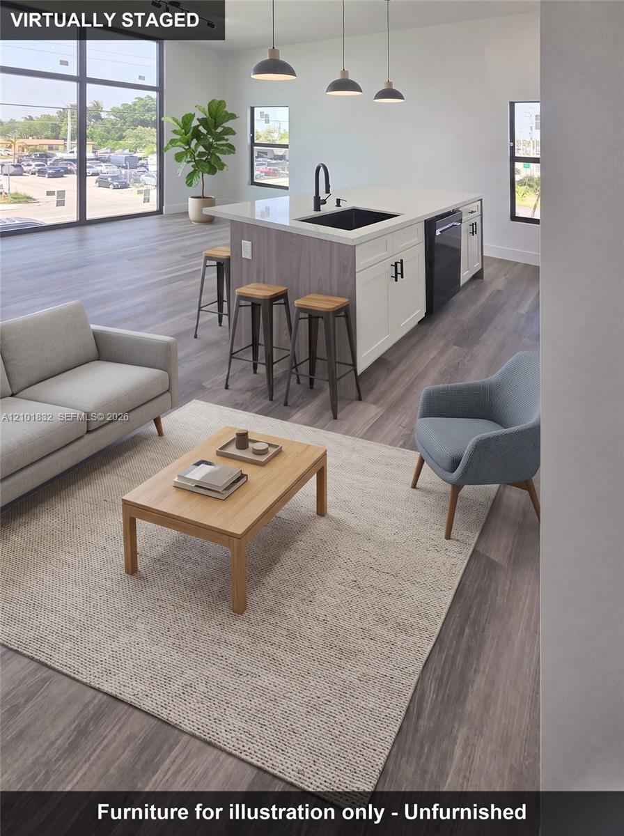Kitchen island featuring quartz countertops, two-tone cabinetry, a black undermount sink, and three pendant lights, finished with wood-finish flooring and floor-to-ceiling windows
