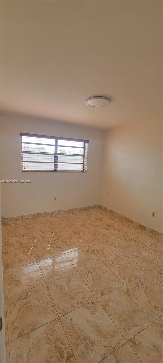 Interior room featuring large-format ceramic tile flooring, neutral wall tones, and a flush-mount ceiling light fixture