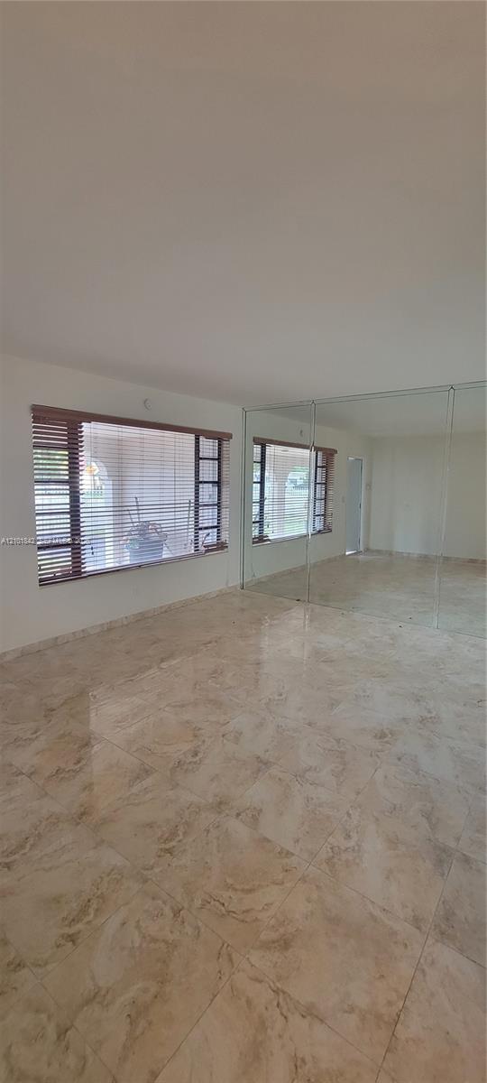 Polished stone-finish flooring, floor-to-ceiling wall mirrors, and large rectangular windows with wooden blinds
