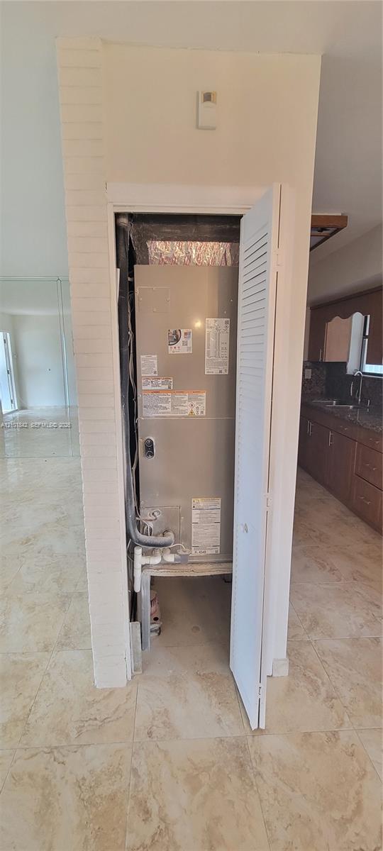 Dedicated utility closet featuring a metallic HVAC air handler unit and louvered door access