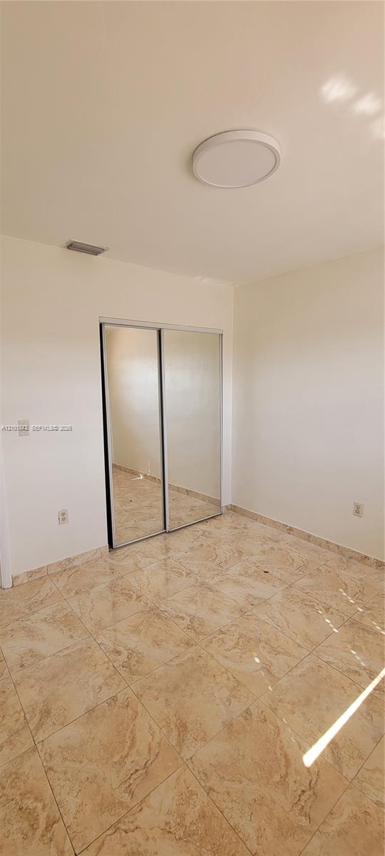 Neutral-toned tile flooring, flush-mount circular ceiling lighting, and sliding mirror-panel closet doors