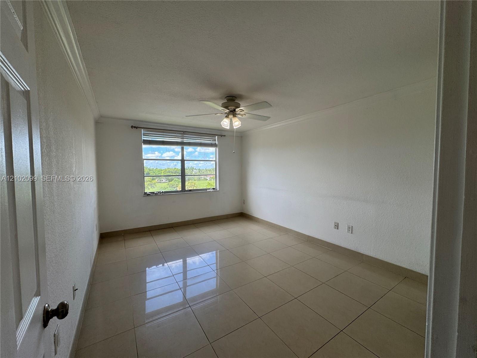 Neutral interior featuring polished tile flooring, crown molding, a multi-light ceiling fan, and large window with horizontal blinds