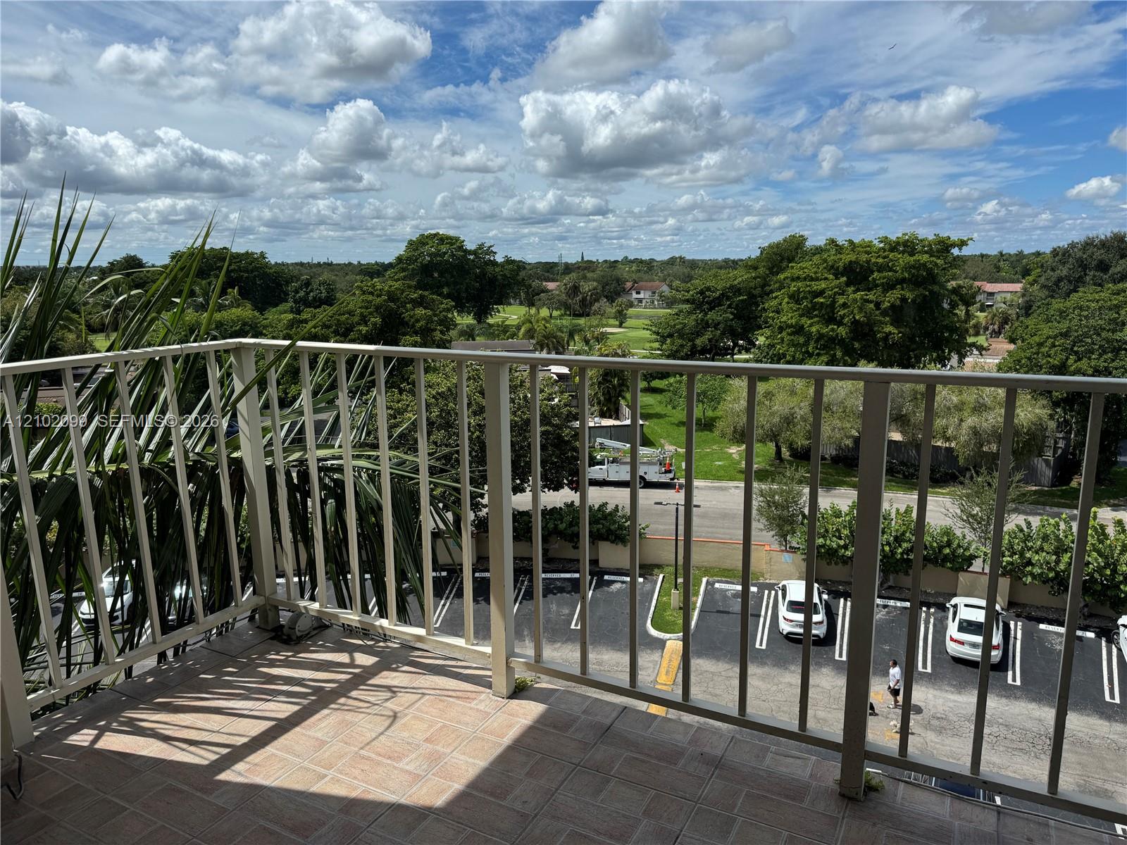 Elevated balcony featuring neutral-toned tile flooring and a white metal railing