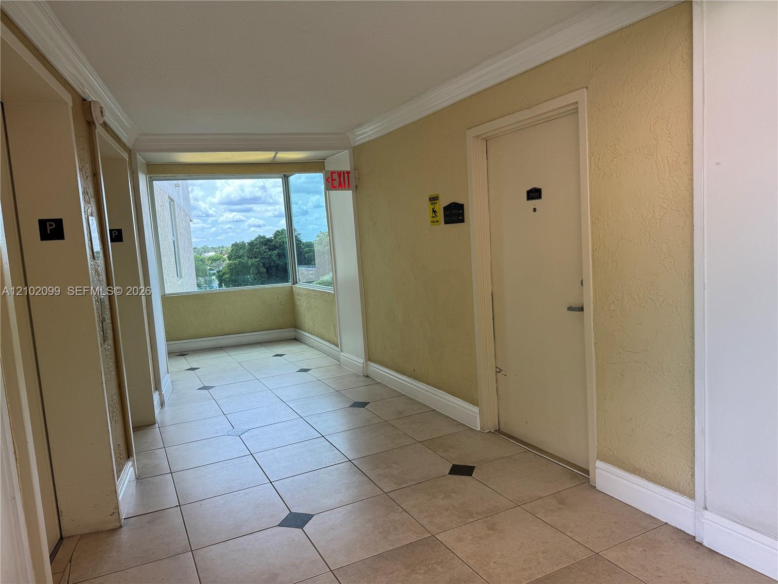 Tiled flooring with geometric inlay, crown molding, and floor-to-ceiling windows