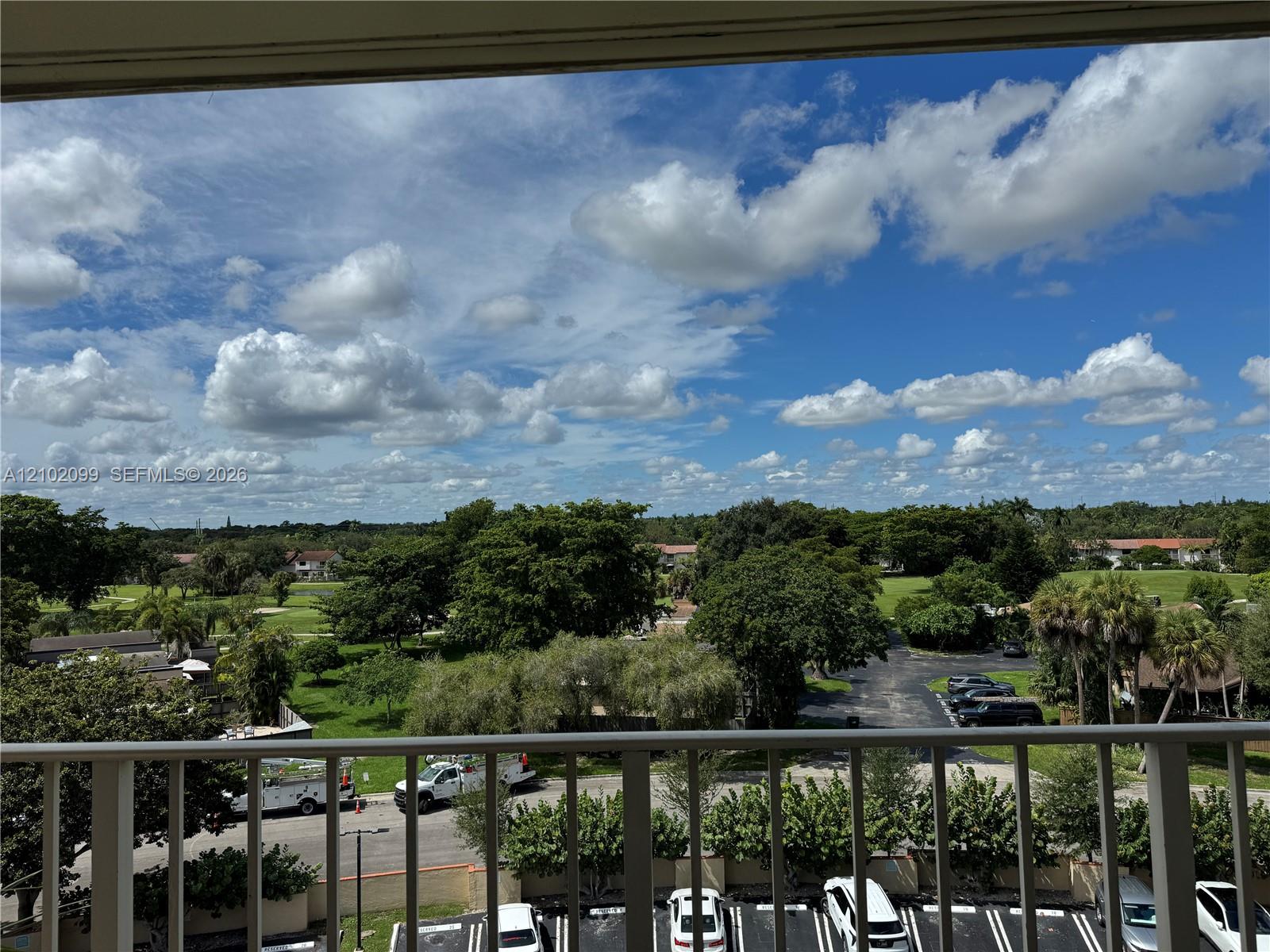 Elevated balcony with vertical metal railing overlooking expansive green space and mature trees