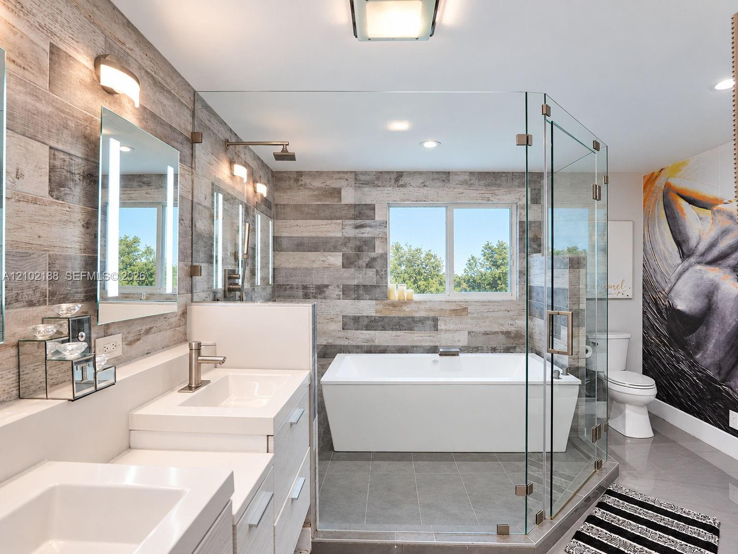 Dual-vanity cabinet with quartz countertops, wood-finish wall paneling, freestanding soaking tub, and glass-enclosed shower with tile flooring