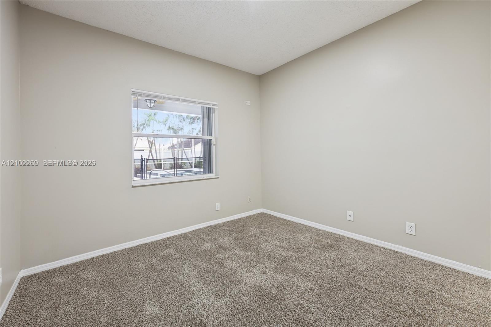 Neutral-toned interior room featuring wall-to-wall carpeting and a single-hung window with integrated blinds