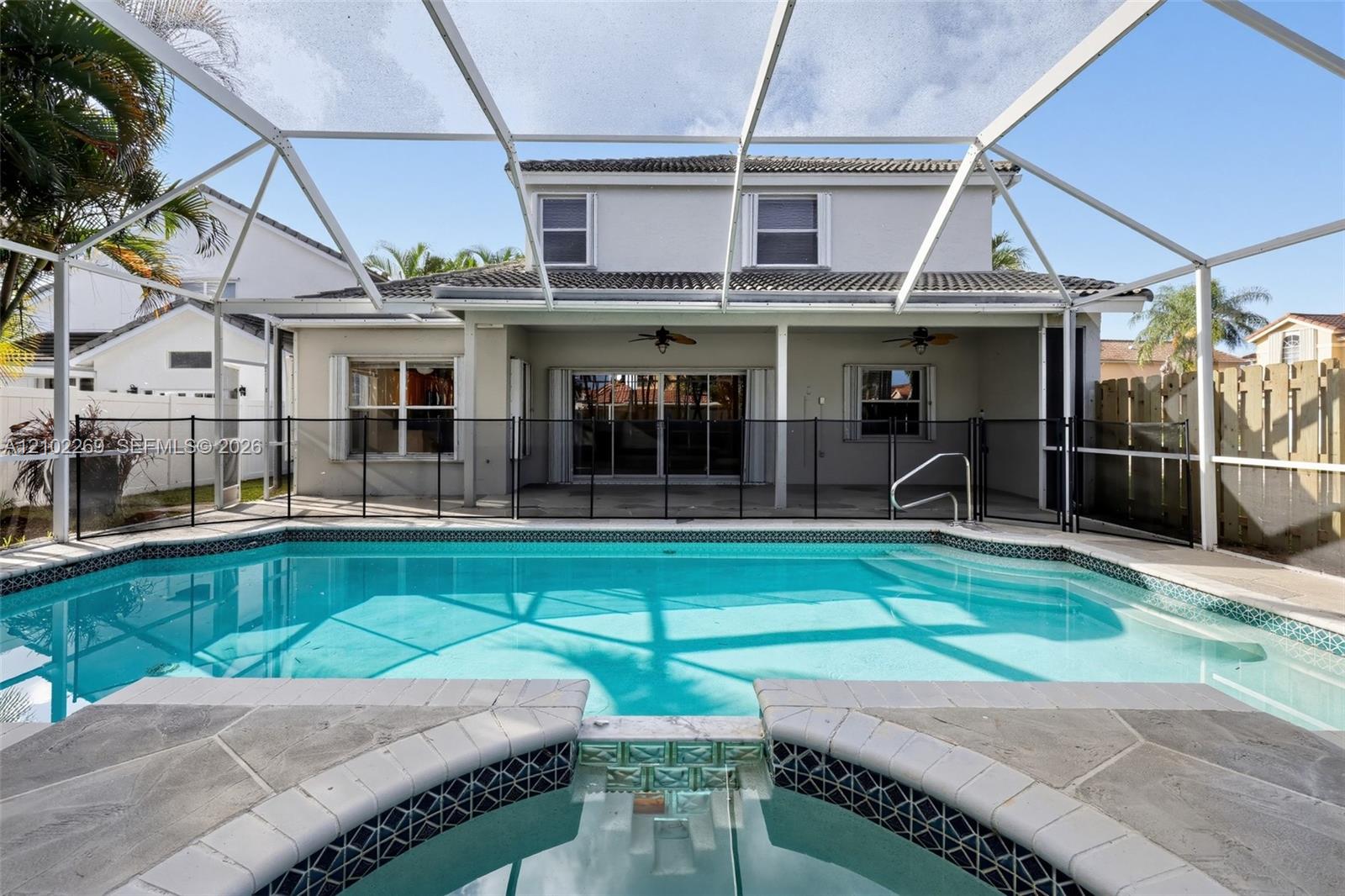Screened-in patio featuring a swimming pool, integrated spa, covered lanai, and installed safety fencing