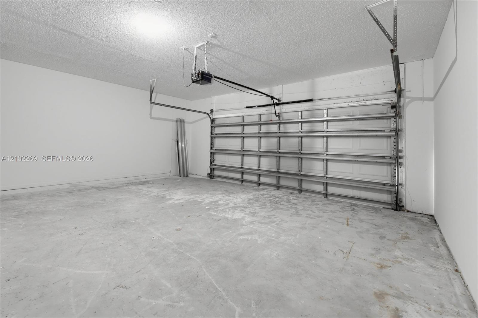 Enclosed garage featuring finished white walls, a concrete floor, and an automated overhead door system