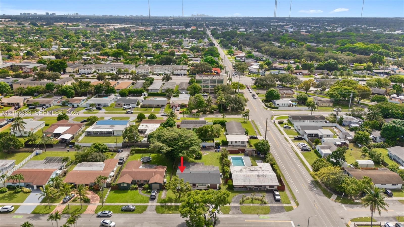 Aerial perspective of a residential property featuring a pitched roof, mature canopy trees, and a concrete driveway