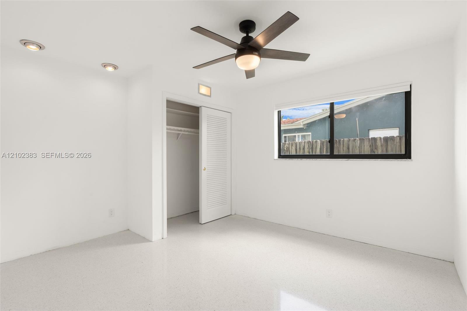 Bedroom 1 Neutral-toned terrazzo flooring, recessed lighting, ceiling fan with integrated light, and louvered closet door