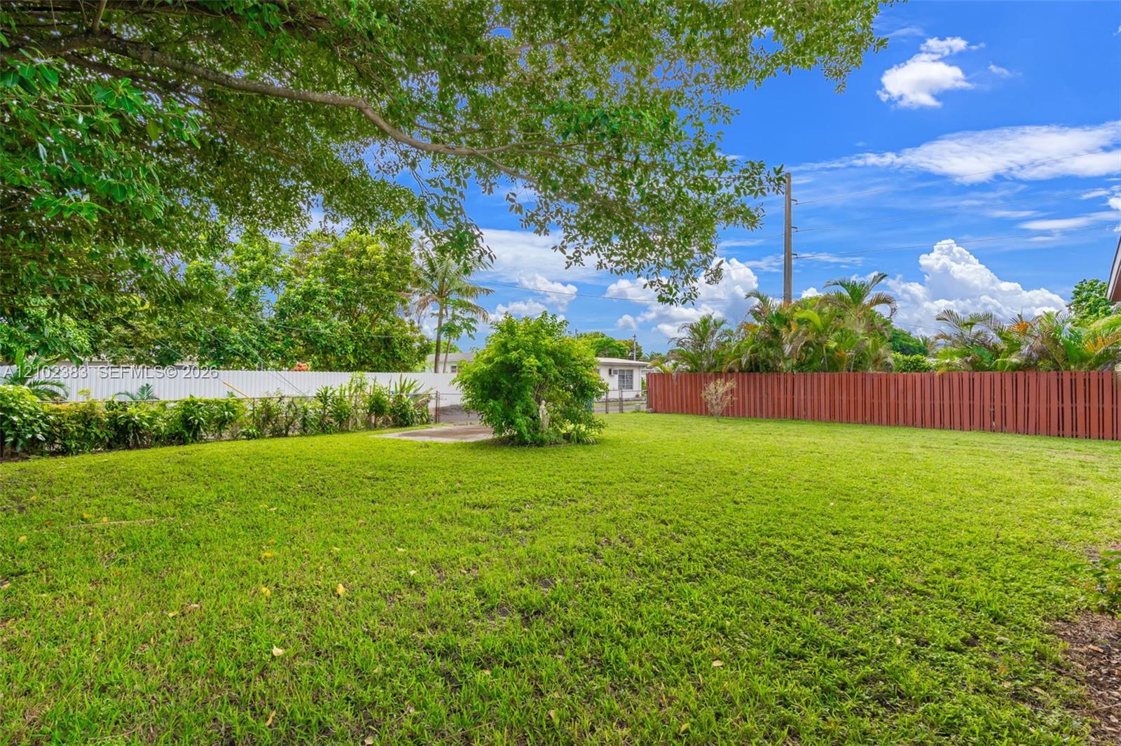 Expansive backyard featuring a level lawn, mature trees, and perimeter fencing