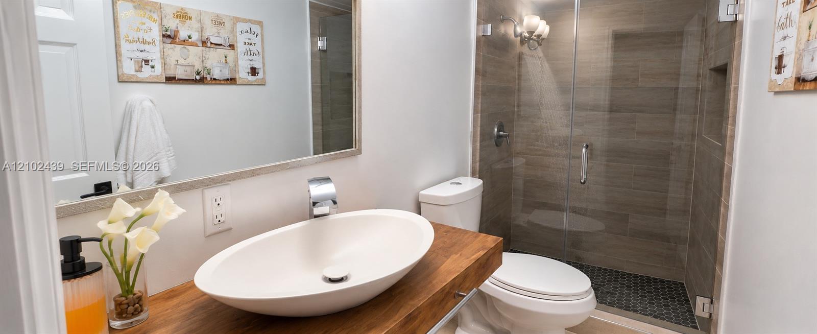 Vanity with a wood-finish countertop, vessel sink, and chrome faucet