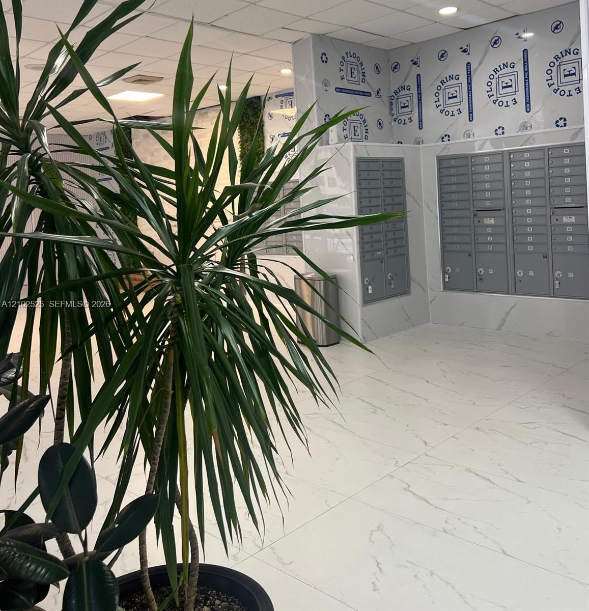 Lobby featuring large-format stone-finish flooring, full-height wall cladding, and integrated metal mailboxes with individual locks